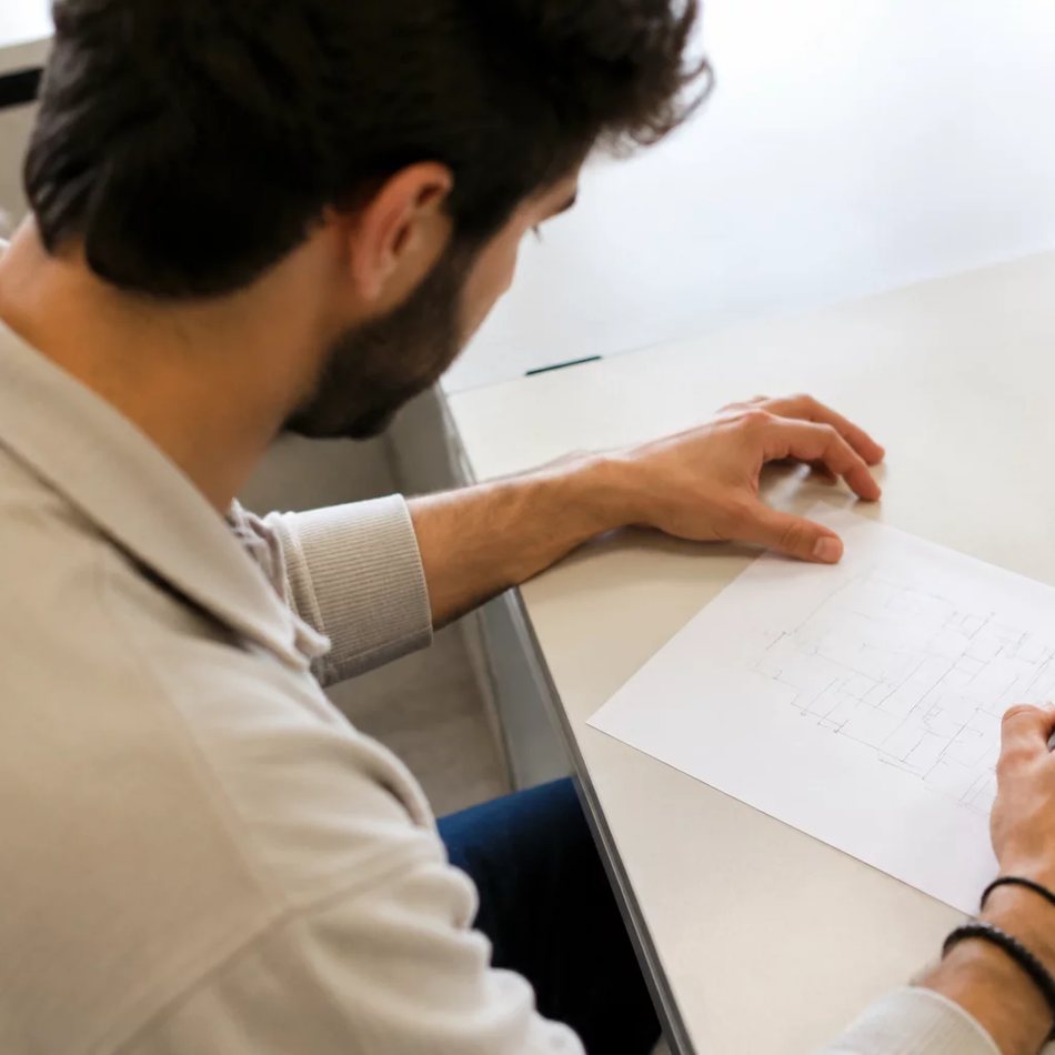 Duas pessoas relendo num tablet as notas da rodada anterior, apoiadas na mesa de madeira